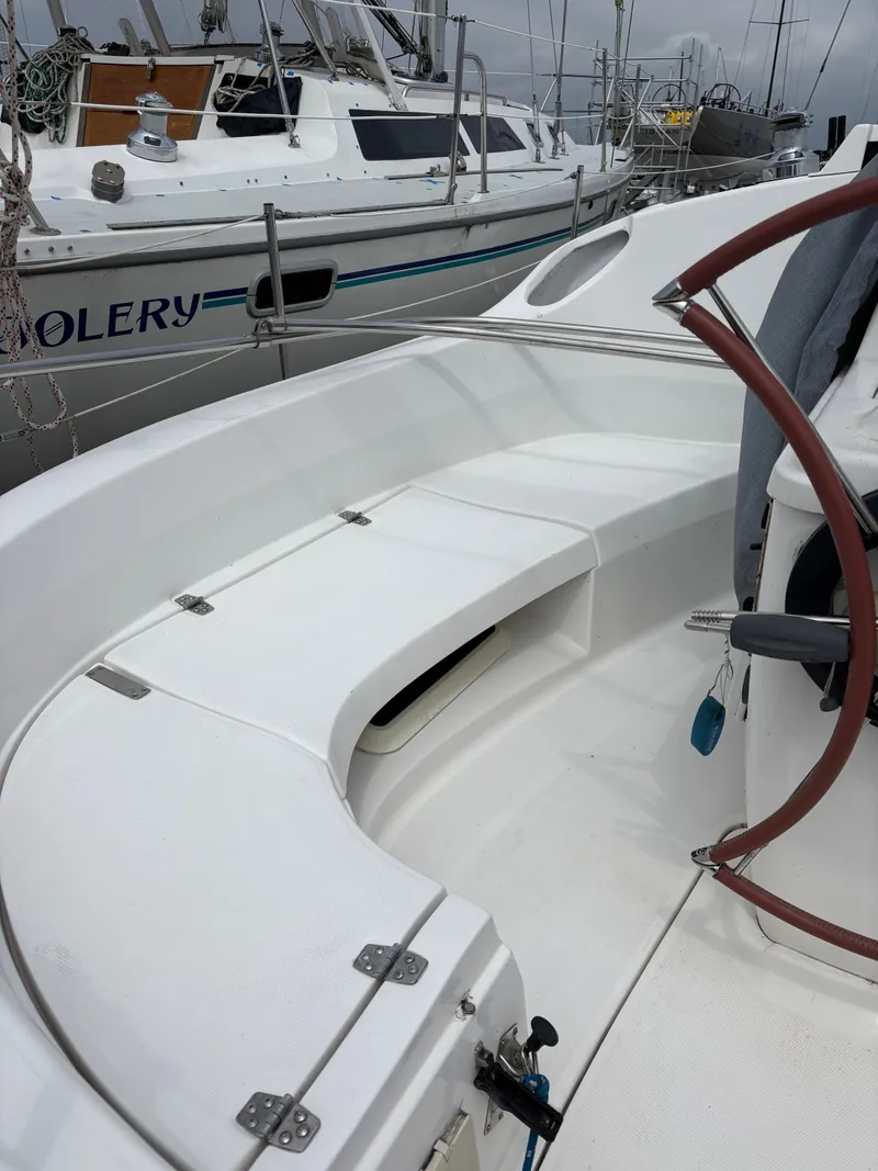 Slide: The Image of 2001 Hunter 320 sailboat cockpit with white seating and steering wheel. - 27