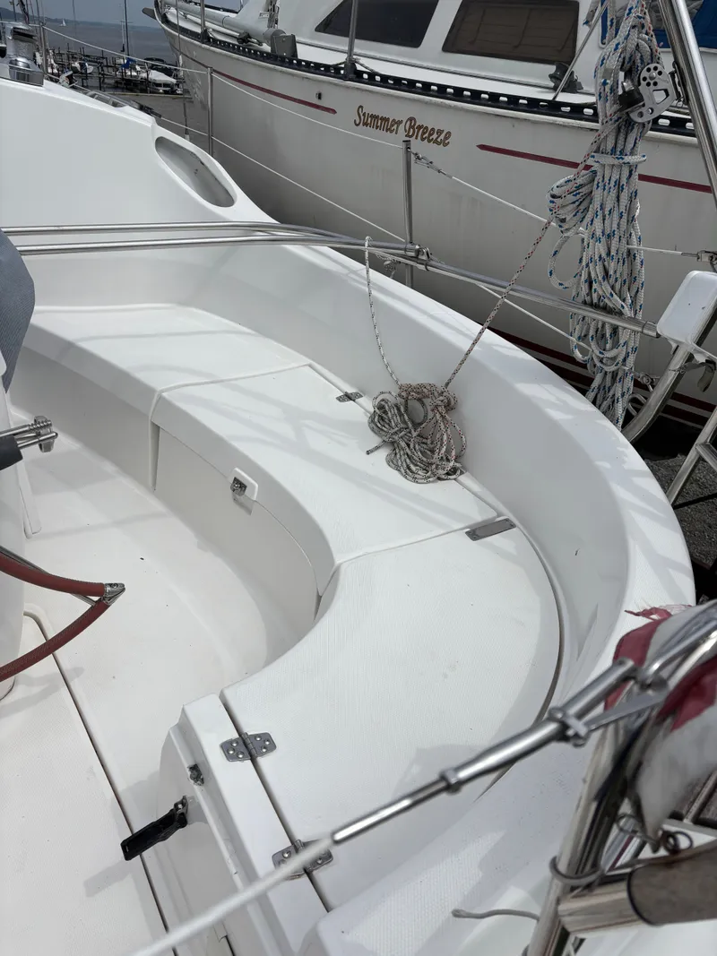 Slide: The Image of 2001 Hunter 320 sailboat cockpit with ropes and seating, docked near another boat. - 29