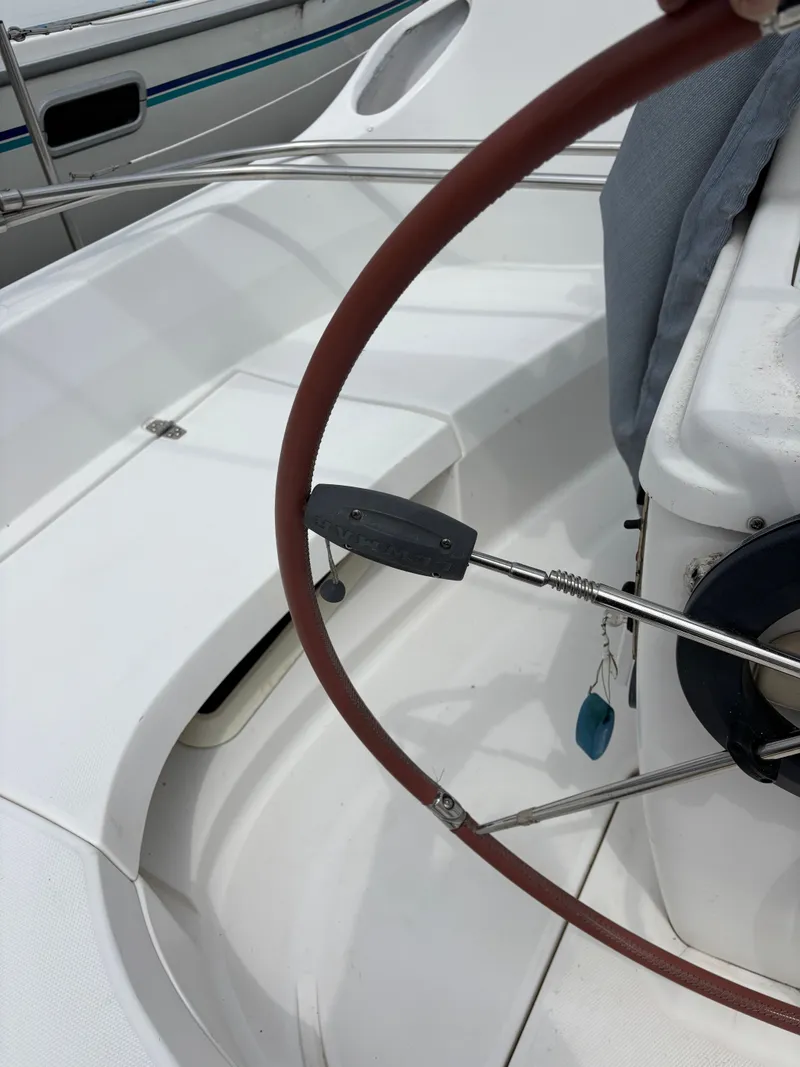 Slide: The Image of Steering wheel of a 2001 Hunter 320 sailboat, featuring a red grip and control panel. - 32