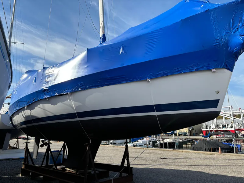 Slide: The Image of 2001 Hunter 320 sailboat covered in blue tarp, docked at a marina. - 4