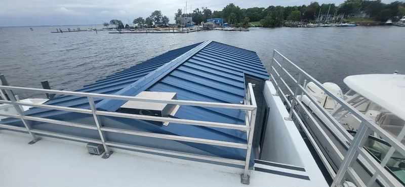 Slide: The Image of 2020 Destination Yachts 16x45 Condo Series houseboat with blue roof on a lake. - 22