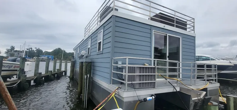 Slide: The Image of 2020 Destination Yachts 16x45 Condo Series houseboat docked on a cloudy day. - 2