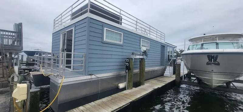 Slide: The Image of 2020 Destination Yachts 16x45 Condo Series houseboat docked beside a yacht. - 27