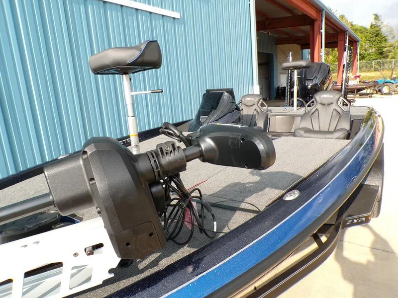 Slide: The Image of 2025 Skeeter ZXR20 boat with advanced trolling motor and seating, parked near a blue building. - 14