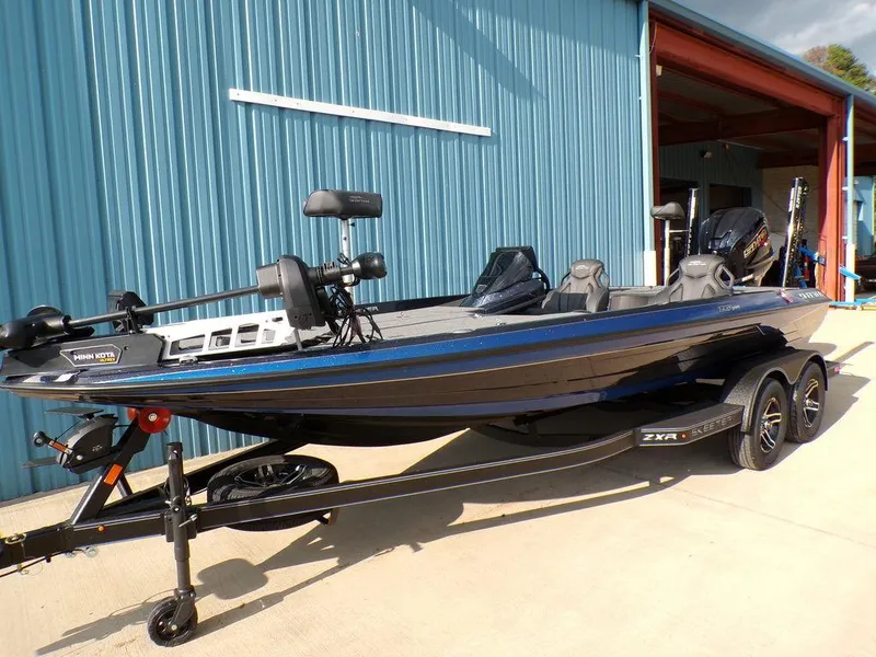 Slide: The Image of 2025 Skeeter ZXR20 bass boat with trailer, parked outside a blue building. - 4