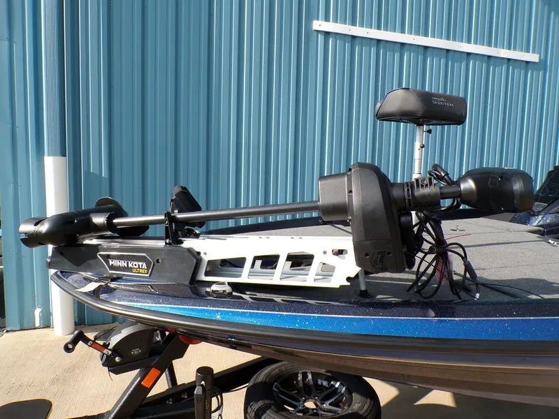 Slide: The Image of 2025 Skeeter ZXR20 boat with Minn Kota trolling motor, parked by a blue building. - 8