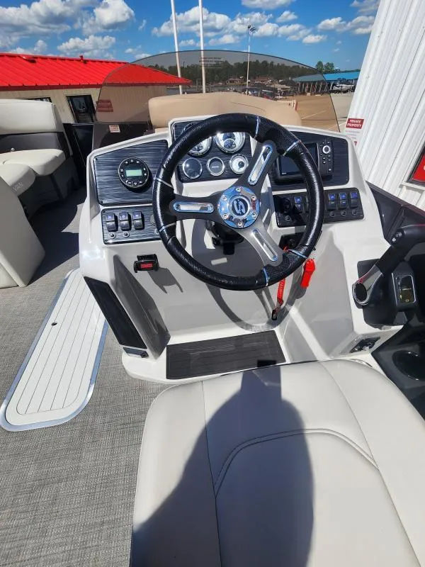 Slide: The Image of 2024 Sylvan Mirage X3 boat dashboard with steering wheel and controls under a blue sky. - 16