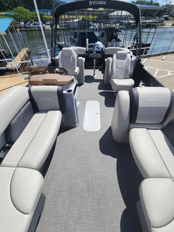 Slide: The Image of 2024 Sylvan Mirage X3 pontoon boat with spacious seating and modern design at a marina. - 6