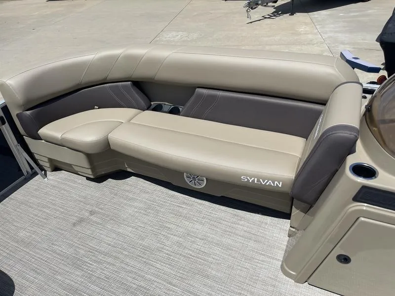 Slide: The Image of 2024 Sylvan Mirage 8524 LZ boat interior with beige seating and cup holders. - 11