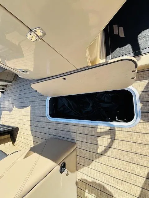 Slide: The Image of 2024 Starcraft SLS-3 boat storage compartment with open lid on beige deck. - 15