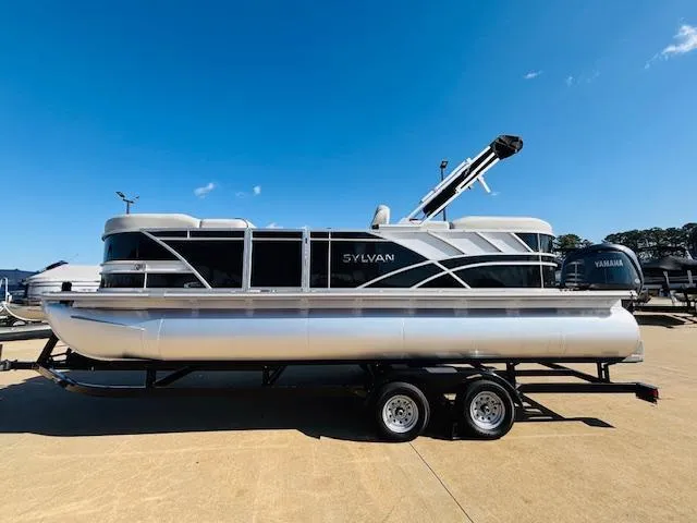 Slide: The Image of 2024 Sylvan Mirage 8522 LZ pontoon boat on trailer under clear blue sky. - 4