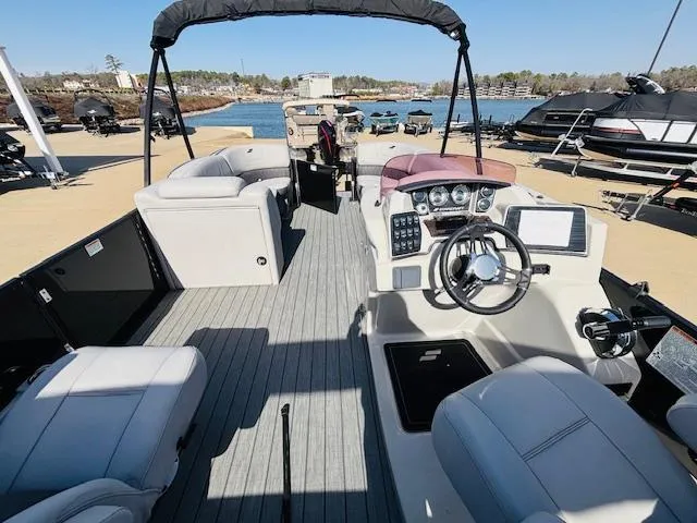 Slide: The Image of 2023 Starcraft SLS-5 Q DH pontoon boat interior with helm and seating, docked by the lake. - 12