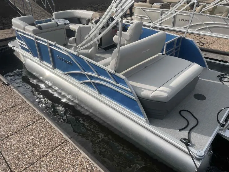 Slide: The Image of 2024 Sylvan MIRAGE 822 CLZ DH pontoon boat with blue accents docked. - 5