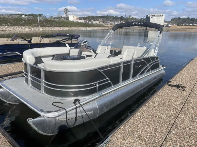 Slide: The Image of 2024 Sylvan MIRAGE 822 CLZ DH pontoon boat docked on a calm lake. - 1