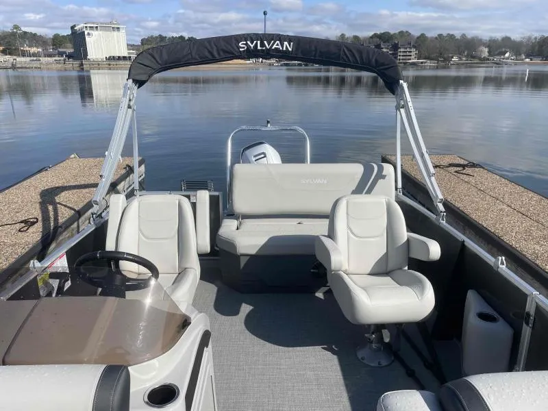 Slide: The Image of 2024 Sylvan MIRAGE 822 CLZ DH pontoon boat interior with seating, docked on a calm lake. - 11