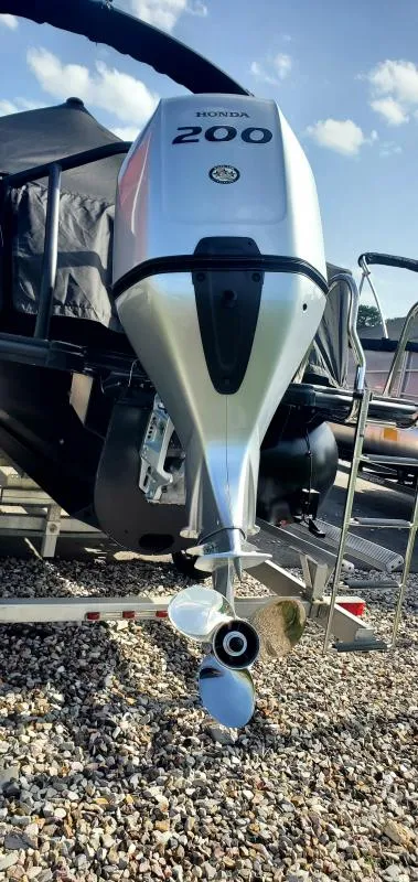 Slide: The Image of 2024 Sylvan L-3 RLZ with Honda 200 outboard motor on a gravel surface. - 3