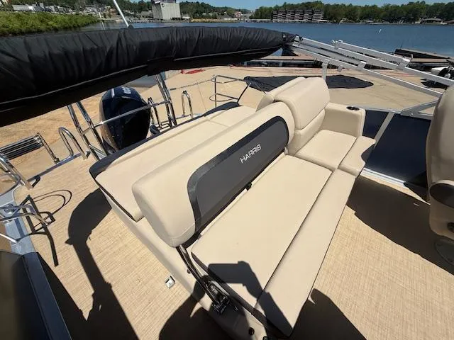 Slide: The Image of 2024 Harris HCX 25 Cruiser 250 boat with beige seating, docked by a lake. - 13