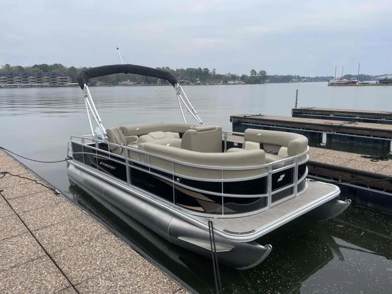 Slide: The Image of 2024 Starcraft LX 20 CB pontoon boat docked on a calm lake. - 3