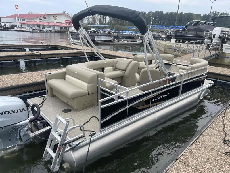Slide: The Image of 2024 Starcraft LX 20 CB pontoon boat docked, featuring beige seating and a Honda outboard motor. - 5