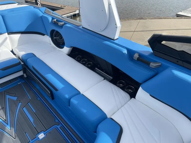 Slide: The Image of 2023 Supra SA 450 boat interior with blue and white seating, cup holders, and speaker. - 24