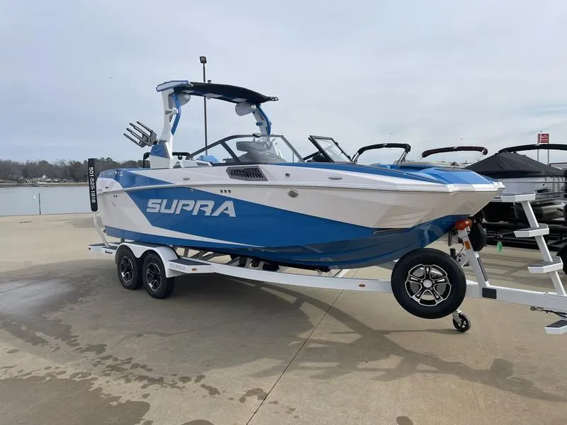 Slide: The Image of 2023 Supra SUPRA SA 450 boat on trailer, blue and white design, parked near water. - 4