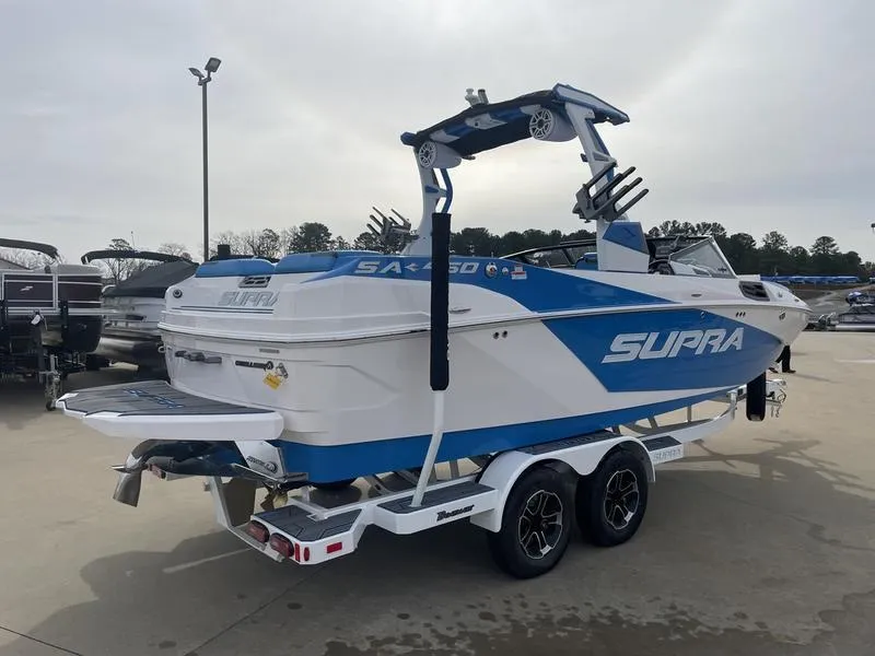 Slide: The Image of 2023 Supra SA 450 boat on trailer, blue and white design, parked outdoors. - 6