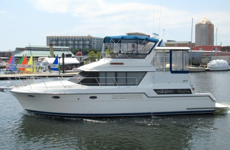 Slide: The Image of 1991 Carver 43 Cockpit Motoryacht docked in a marina, colorful sails in background. - 3