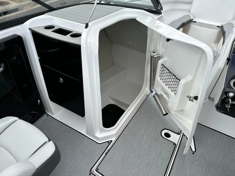 Slide: The Image of 2025 Yamaha Boats AR250 interior cabin with open storage compartment and seating area. - 11
