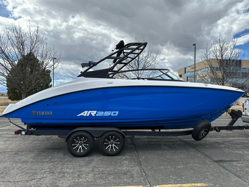 Slide: The Image of 2025 Yamaha AR250 boat in blue on a trailer, parked outdoors under cloudy skies. - 5