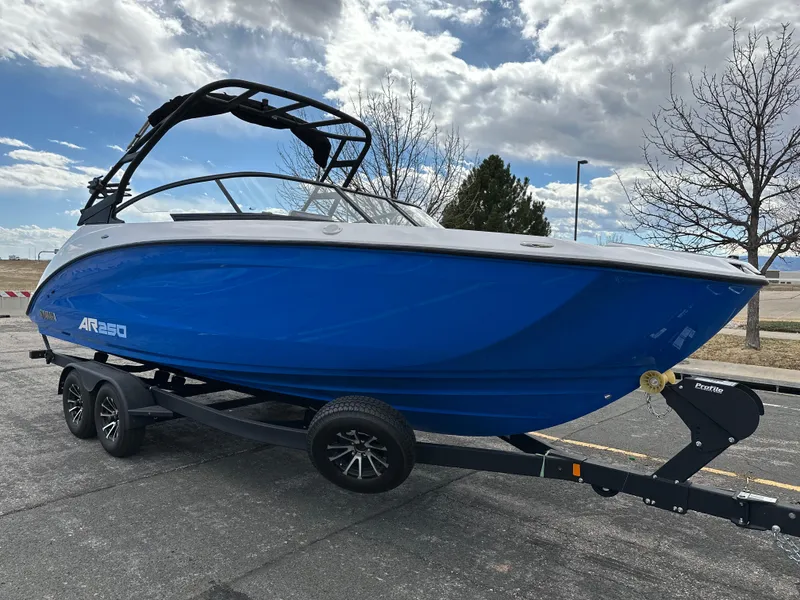 Slide: The Image of 2025 Yamaha Boats AR250 in blue on a trailer, parked outdoors under a cloudy sky. - 6