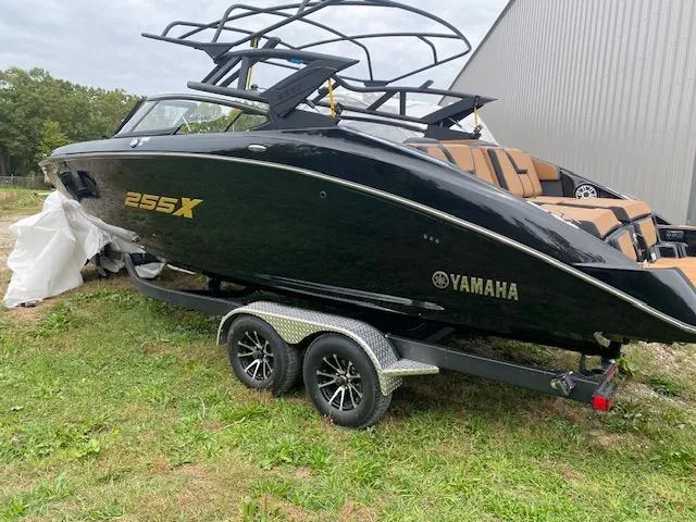 Slide: The Image of 2025 Yamaha Boats 255XD in black on trailer, parked outdoors. - 1