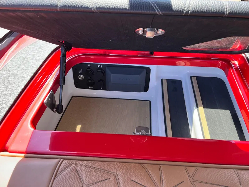 Slide: The Image of 2021 Nautique Super Air Nautique G25 Paragon storage compartment with control panel and cushioned interior. - 21