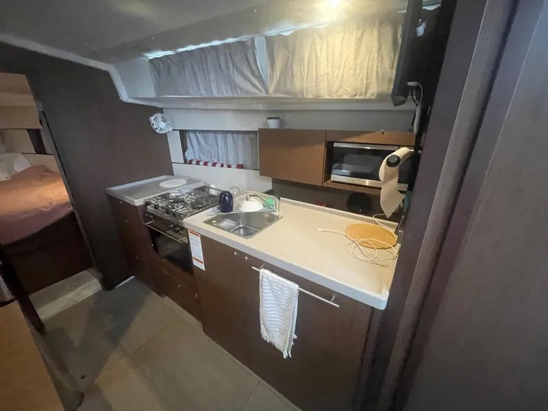 Slide: The Image of Interior of 2022 Beneteau Oceanis 38.1 yacht kitchen with stove, sink, and microwave. - 17