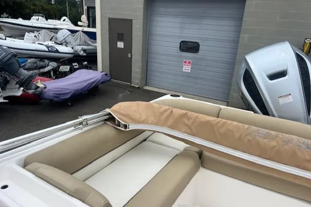 Slide: The Image of 2020 Key West 239 DFS boat interior with beige seating, stored near a garage. - 10