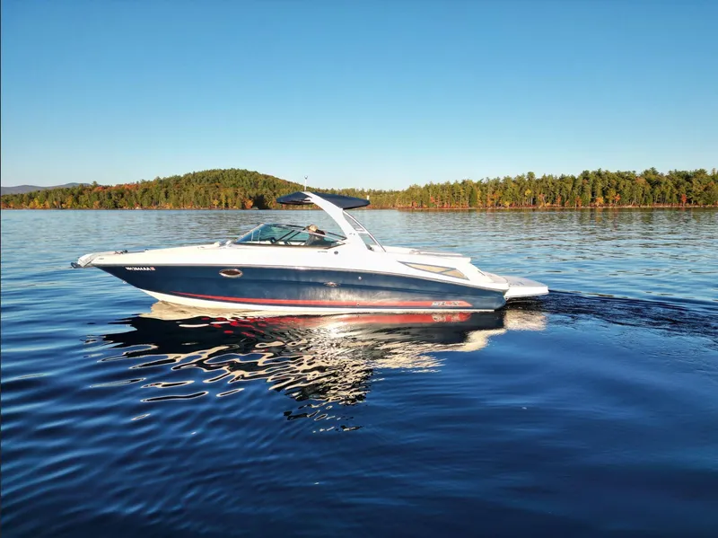 Slide: The Image of 2015 Sea Ray 300 SLX boat cruising on a serene lake under clear blue skies. - 2