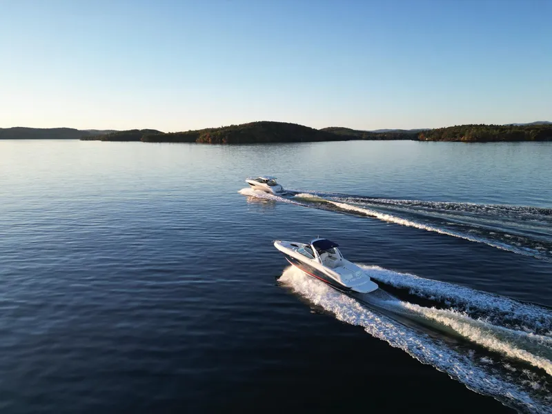 Slide: The Image of 2015 Sea Ray 300 SLX boats cruising on a serene lake at sunset. - 20