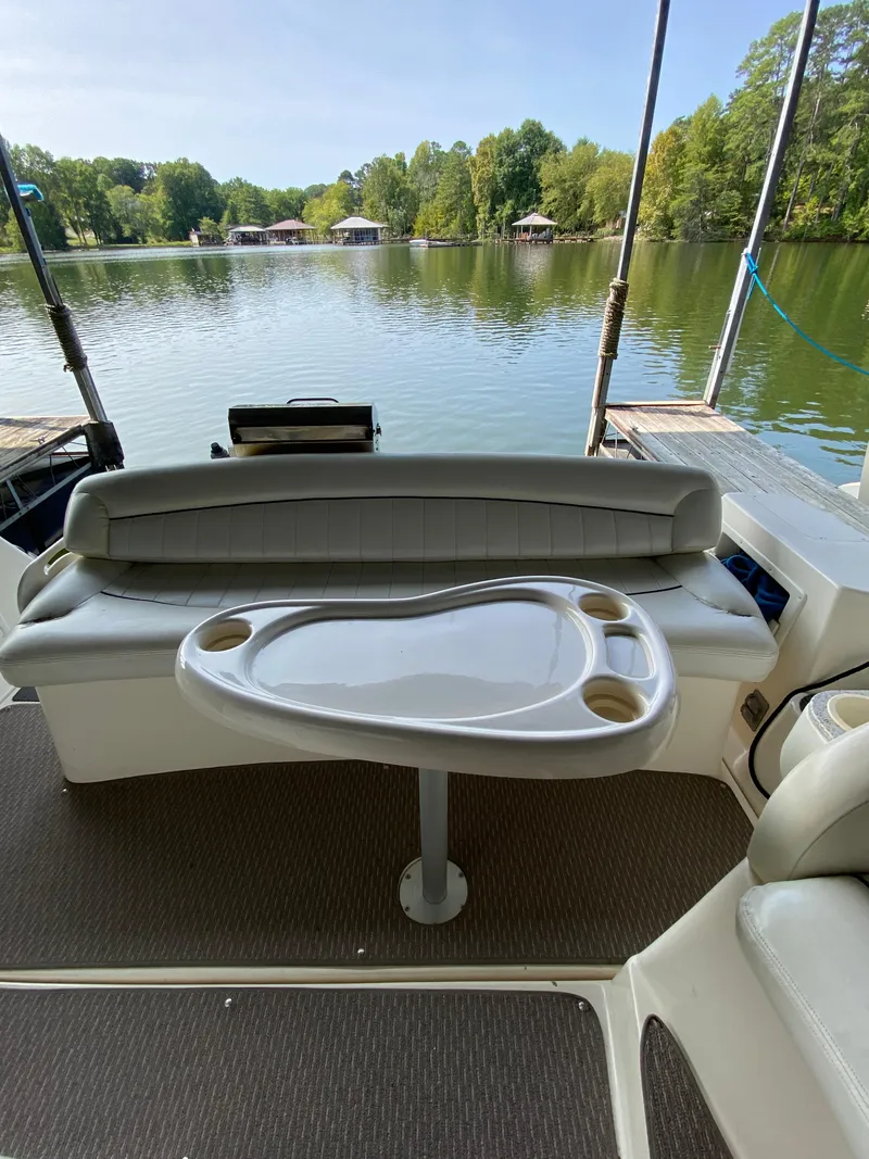 Slide: The Image of Interior of a 2000 Rinker 340 Fiesta Vee boat with seating and table, overlooking a serene lake. - 11