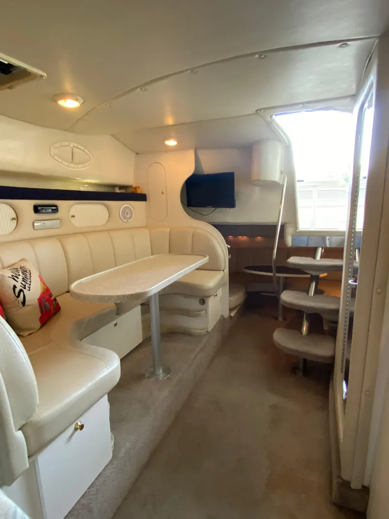 Slide: The Image of Interior of 2000 Rinker 340 Fiesta Vee boat with seating, table, and TV. - 18
