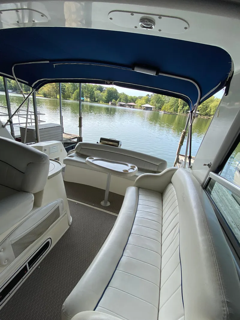 Slide: The Image of 2000 Rinker 340 Fiesta Vee boat interior with seating, table, and lake view. - 10