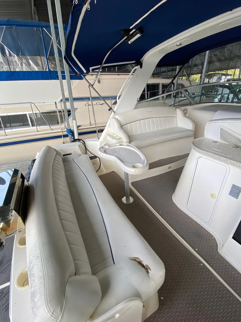 Slide: The Image of Interior of 2000 Rinker 340 Fiesta Vee boat with white seating and blue canopy. - 7