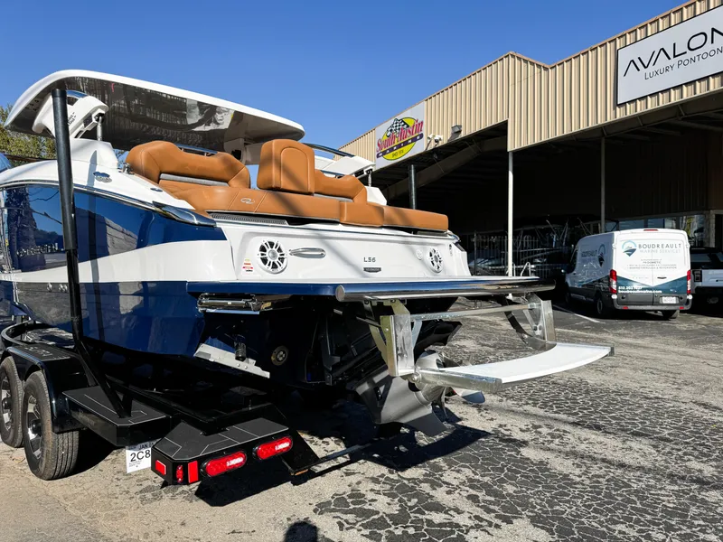 Slide: The Image of 2025 Regal LS6 boat with tan seats, parked outside Avalon Luxury Pontoon dealership. - 9