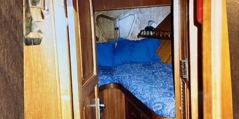 Slide: The Image of Cozy cabin interior of a 1977 Davis 42' boat with wooden furnishings and blue bedding. - 29