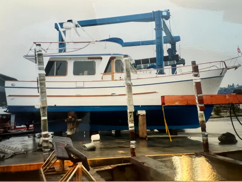 Slide: The Image of 1977 Davis 42' boat on dry dock, undergoing maintenance with a blue and white exterior. - 32
