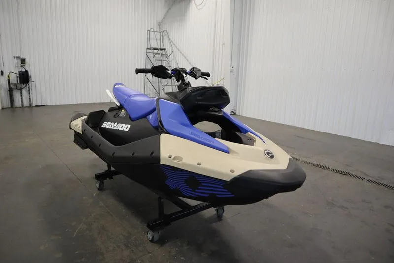 Slide: The Image of 2025 Sea-Doo Spark Trixx jet ski in a showroom, featuring blue and beige design. - 11