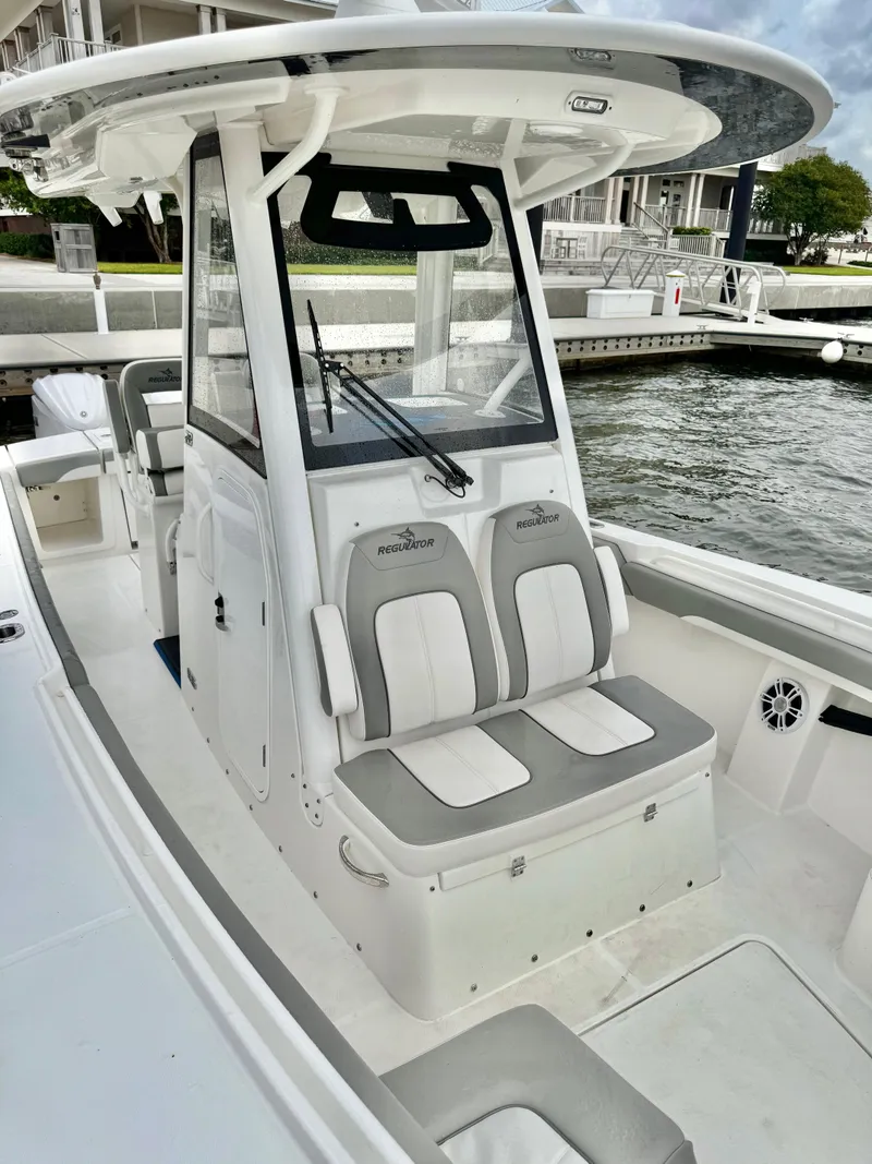 Slide: The Image of 2023 Regulator 28 boat with dual seats and modern console design at a marina. - 13