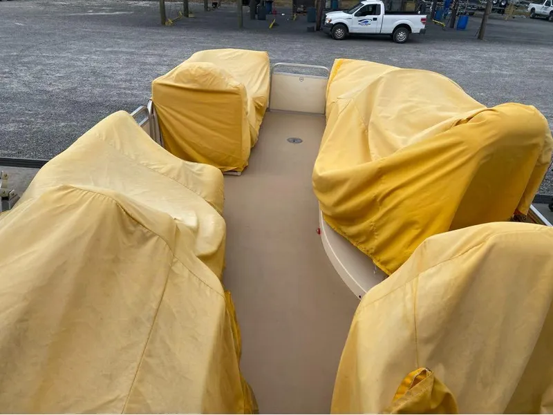 Slide: The Image of 2012 Godfrey AP 240 boat with yellow covers, parked on gravel lot. - 10