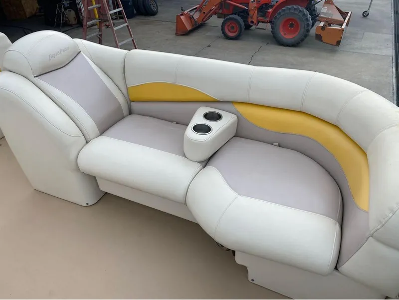 Slide: The Image of 2012 Godfrey AP 240 boat seating with cup holders, featuring white and yellow upholstery. - 12