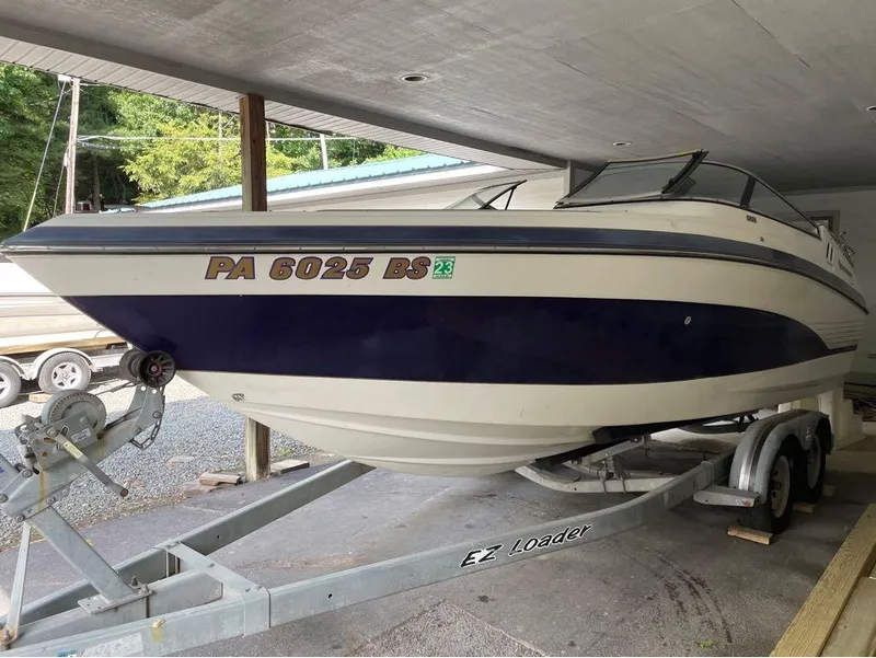 Slide: The Image of 1996 Celebrity 220 boat on EZ Loader trailer, parked under a shelter. - 15