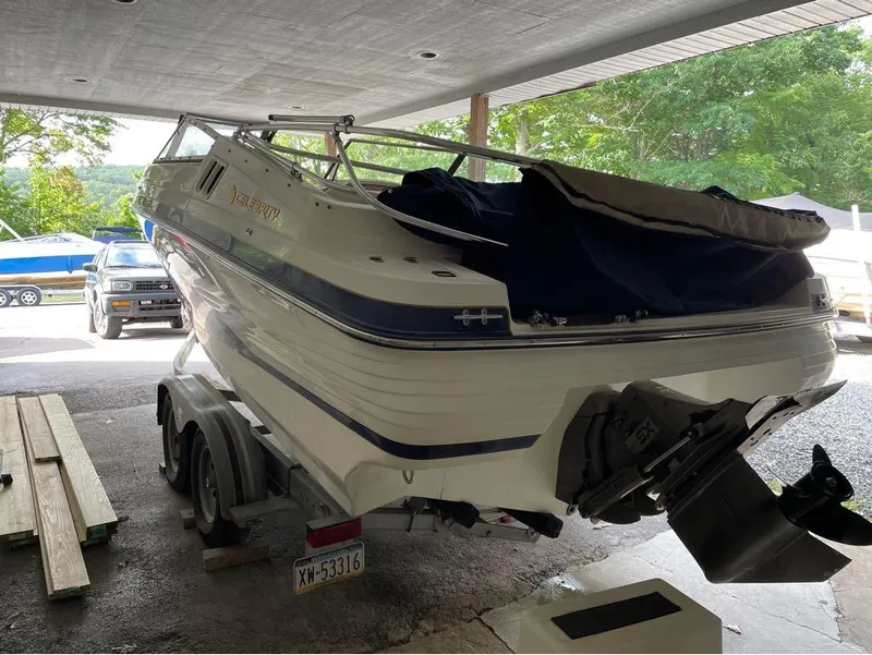 Slide: The Image of 1996 Celebrity 220 boat on trailer under a carport, surrounded by trees. - 7