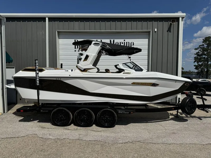 Slide: The Image of 2025 Nautique PARAGON 23 boat on trailer, parked outside a marine facility. - 0